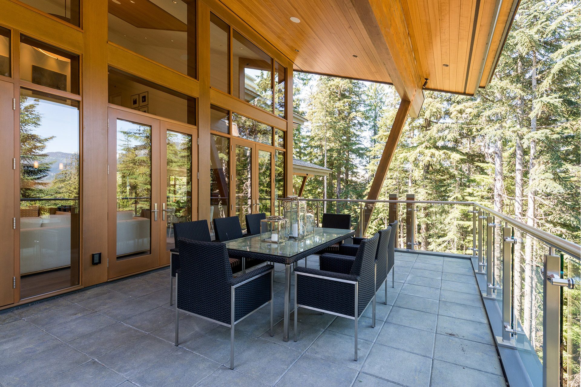 Covered deck with a glass railing and timber posts at a new build residence on Ancient Cedars Lane, Whistler
